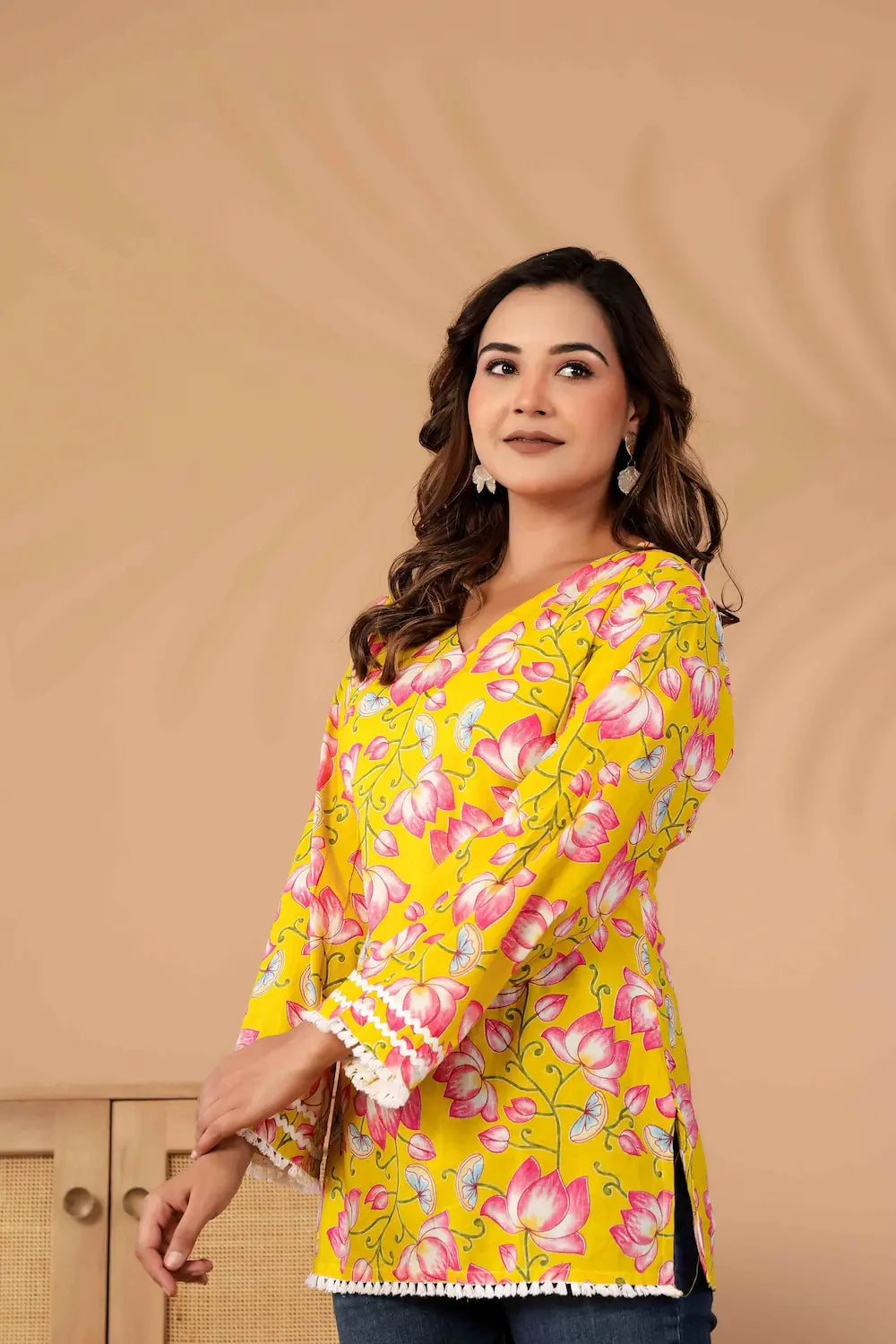 Woman wearing a yellow floral blouse against a beige background