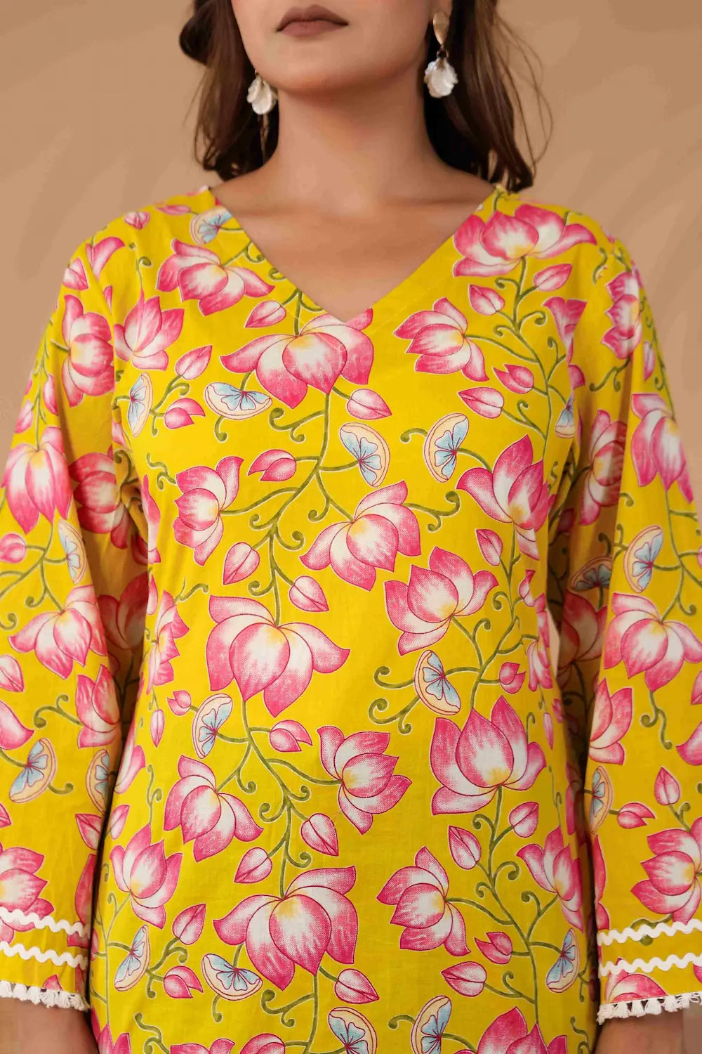 Yellow floral patterned top worn by a person against a beige background