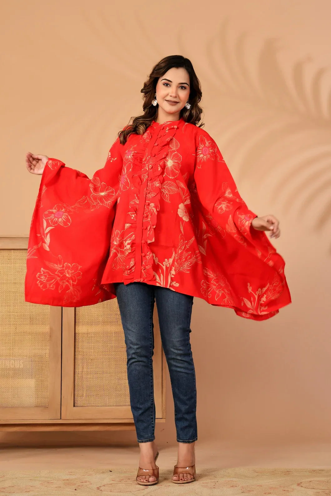 Woman wearing a red floral blouse with blue jeans against a beige background