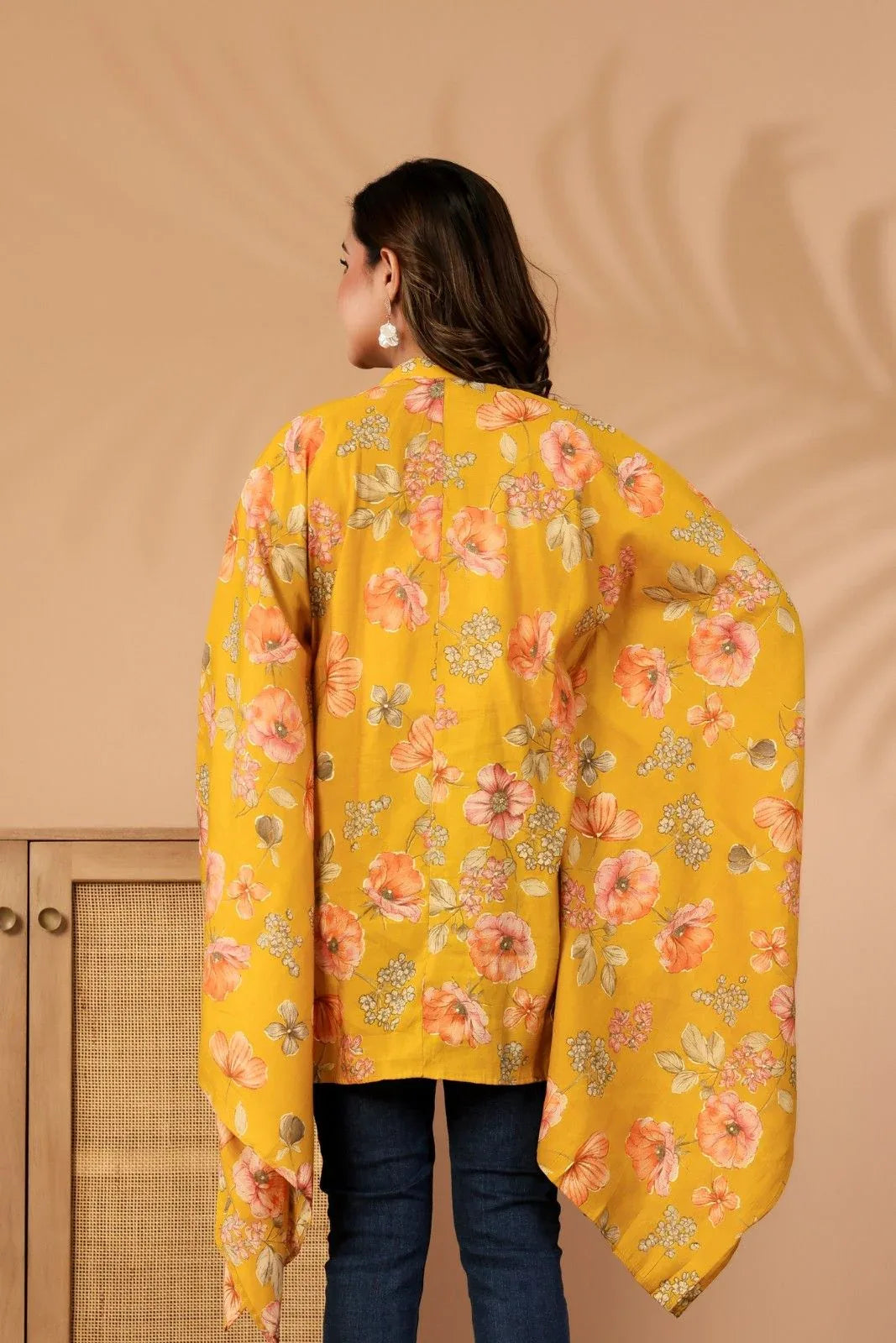 Woman wearing a yellow floral dress against a beige background-YAVASTRAH