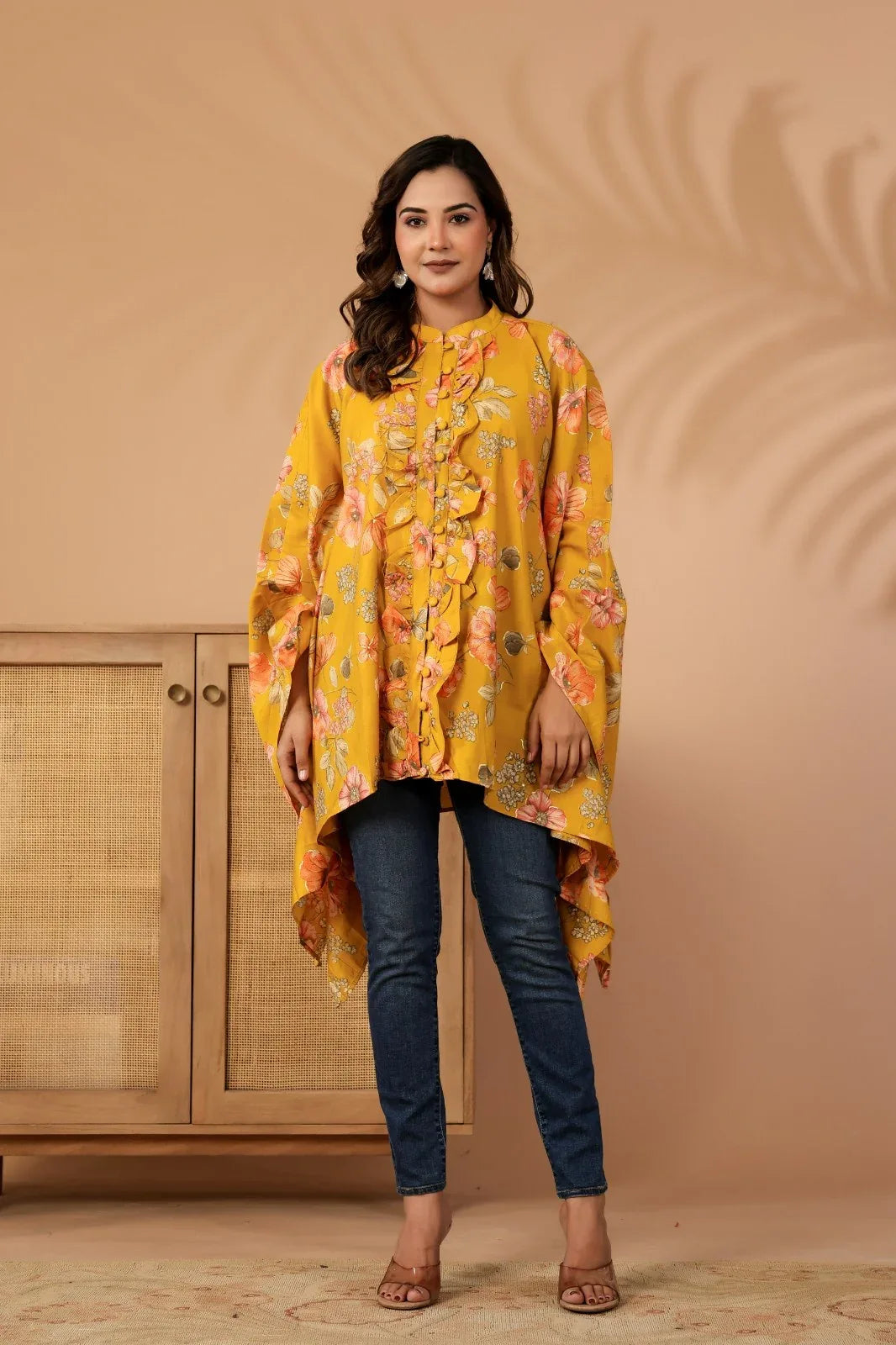 Woman wearing a yellow floral dress against a beige wall-YAVASTRAH