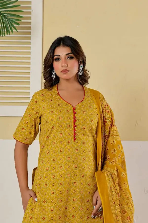 Woman wearing a yellow patterned kurta with a red neckline against a beige wall.