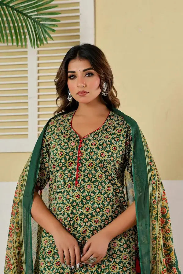Woman wearing a green floral dress with a matching dupatta in an indoor setting.