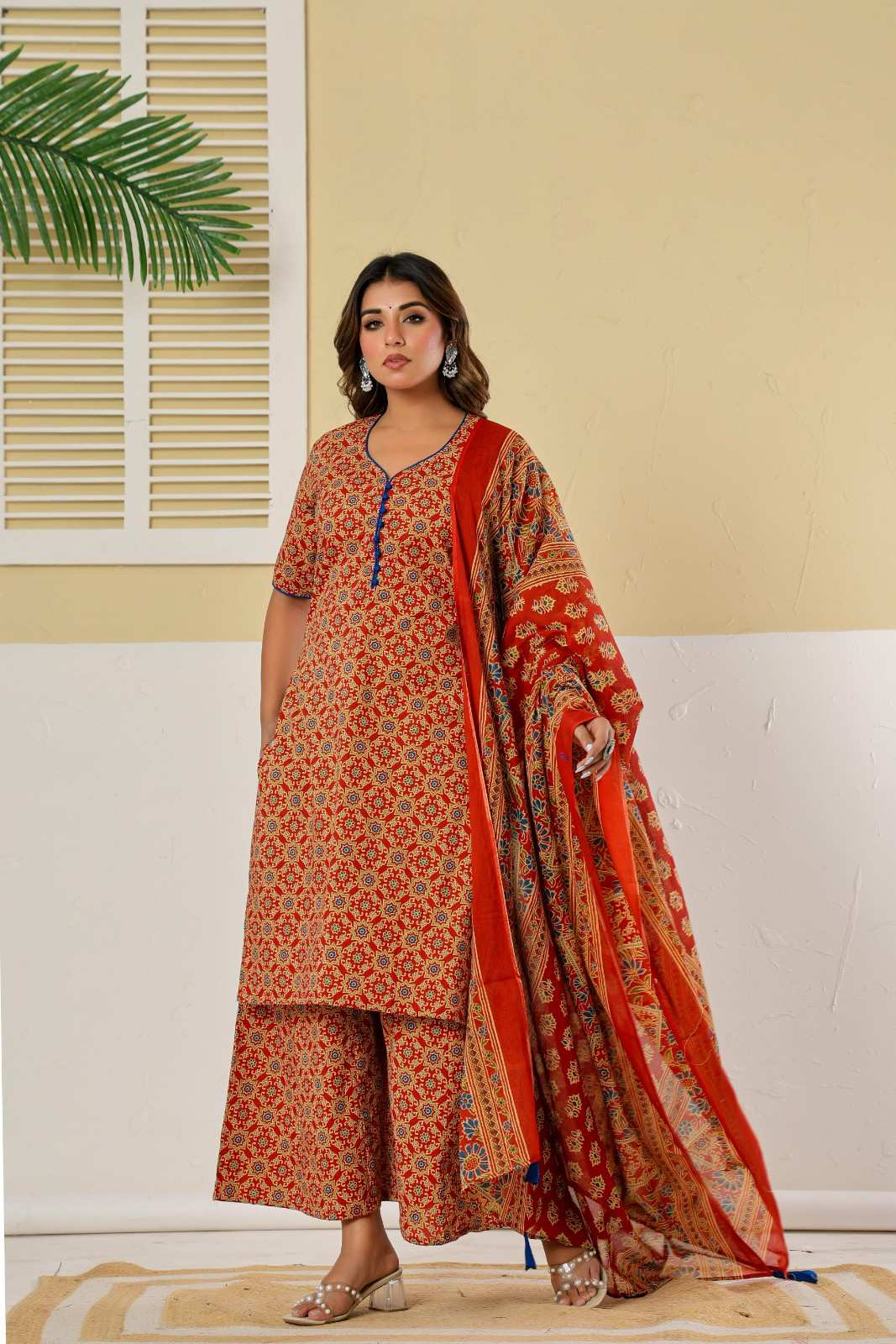 Woman wearing a traditional outfit with a red and orange patterned dupatta against a neutral background - YAVASTRAH