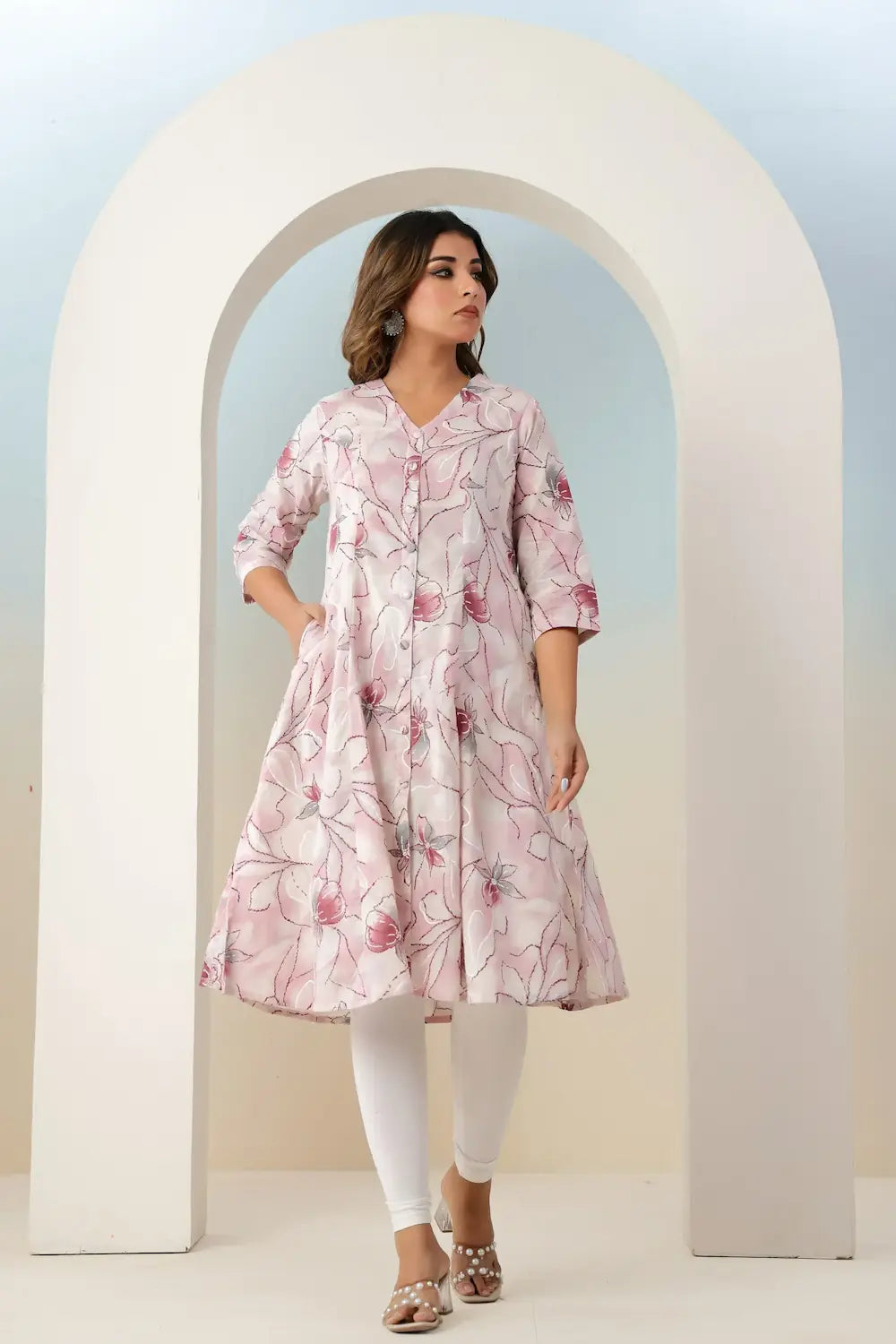Woman wearing a pink floral dress standing in front of an archway.
