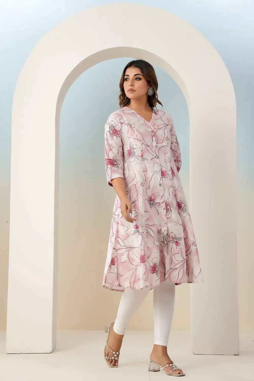 Woman wearing a pink floral dress standing in front of an archway.