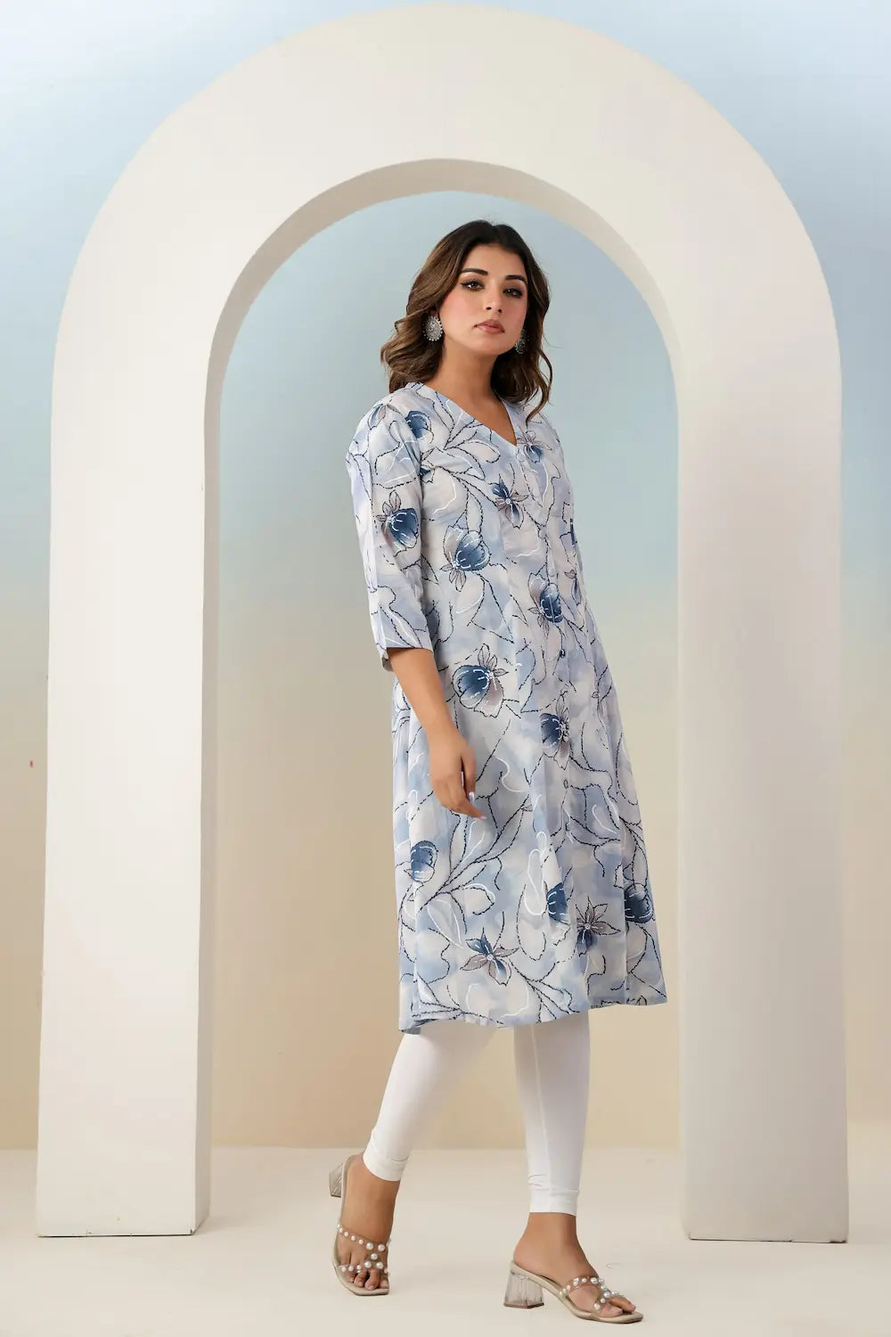Woman wearing a floral dress standing in front of a white archway.