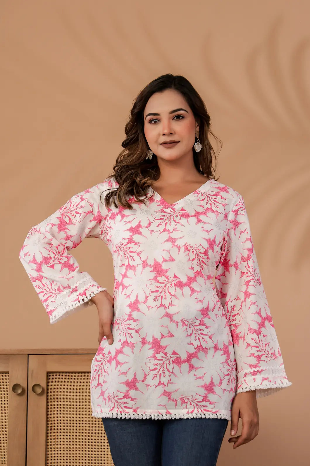 Woman wearing a pink and white floral blouse against a beige background