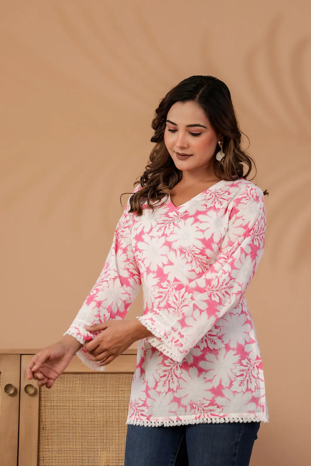 Woman wearing a pink and white floral blouse against a beige background