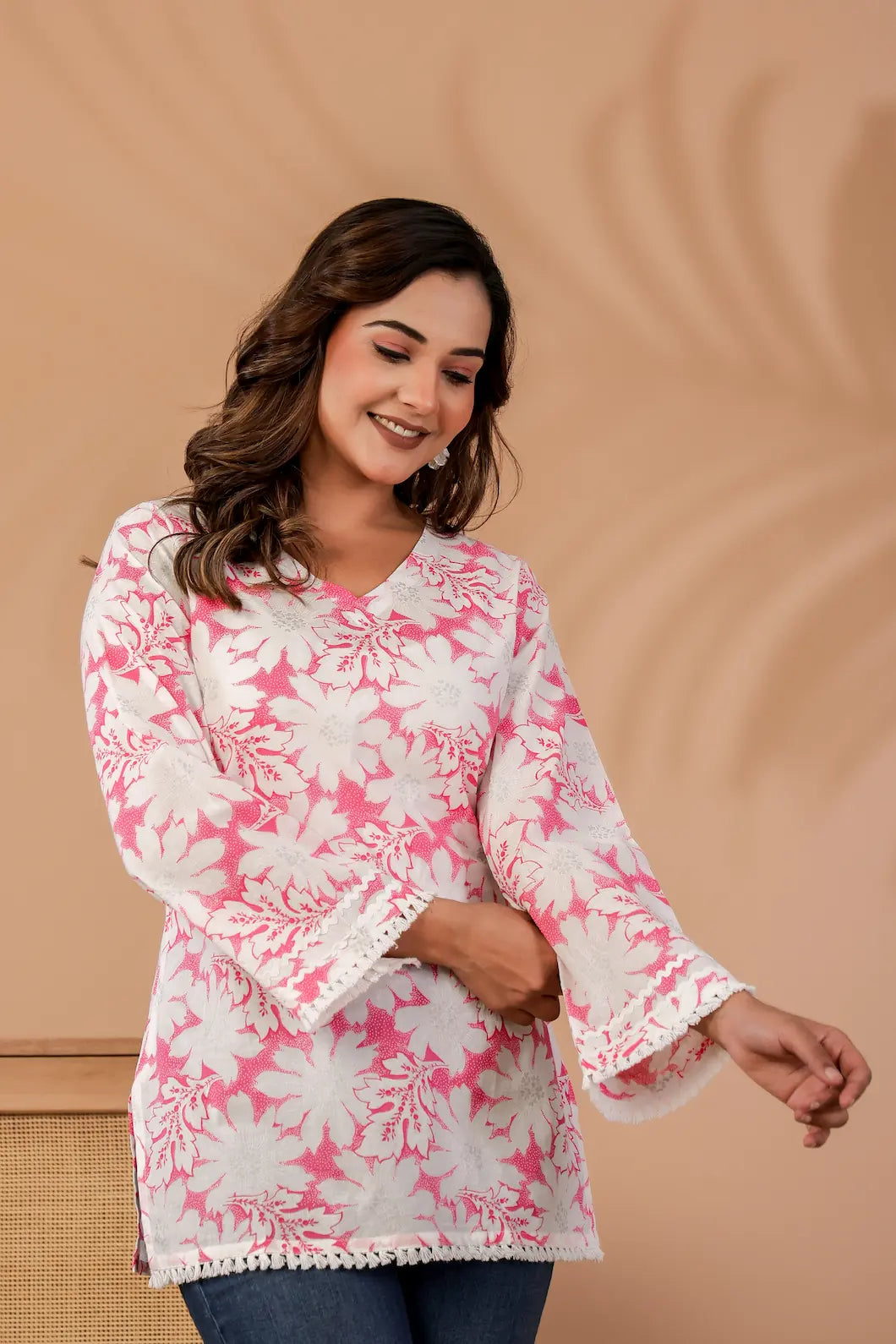 Woman wearing a pink and white floral blouse against a beige background