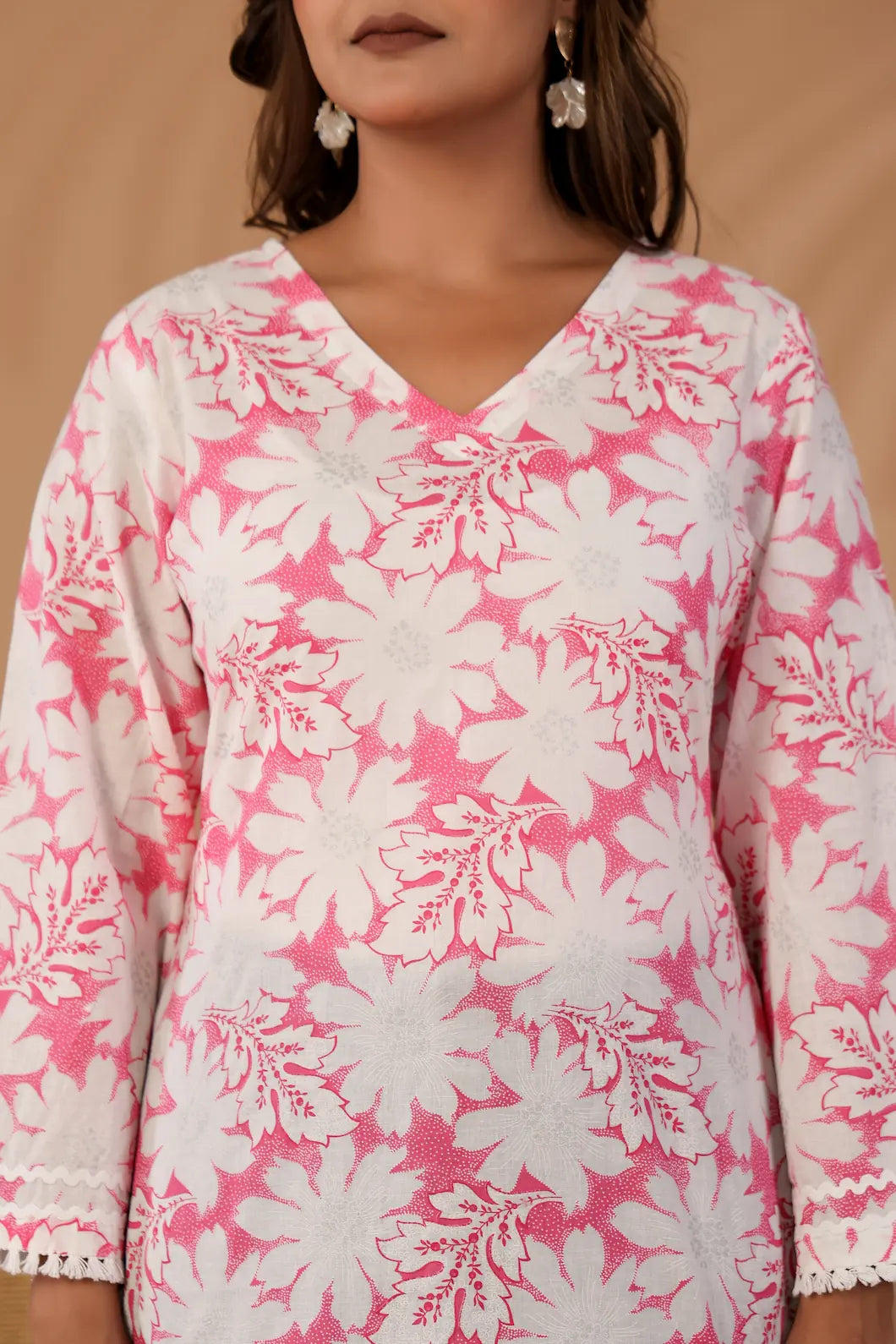 Woman wearing a pink and white floral dress against a beige background-YAVASTRAH