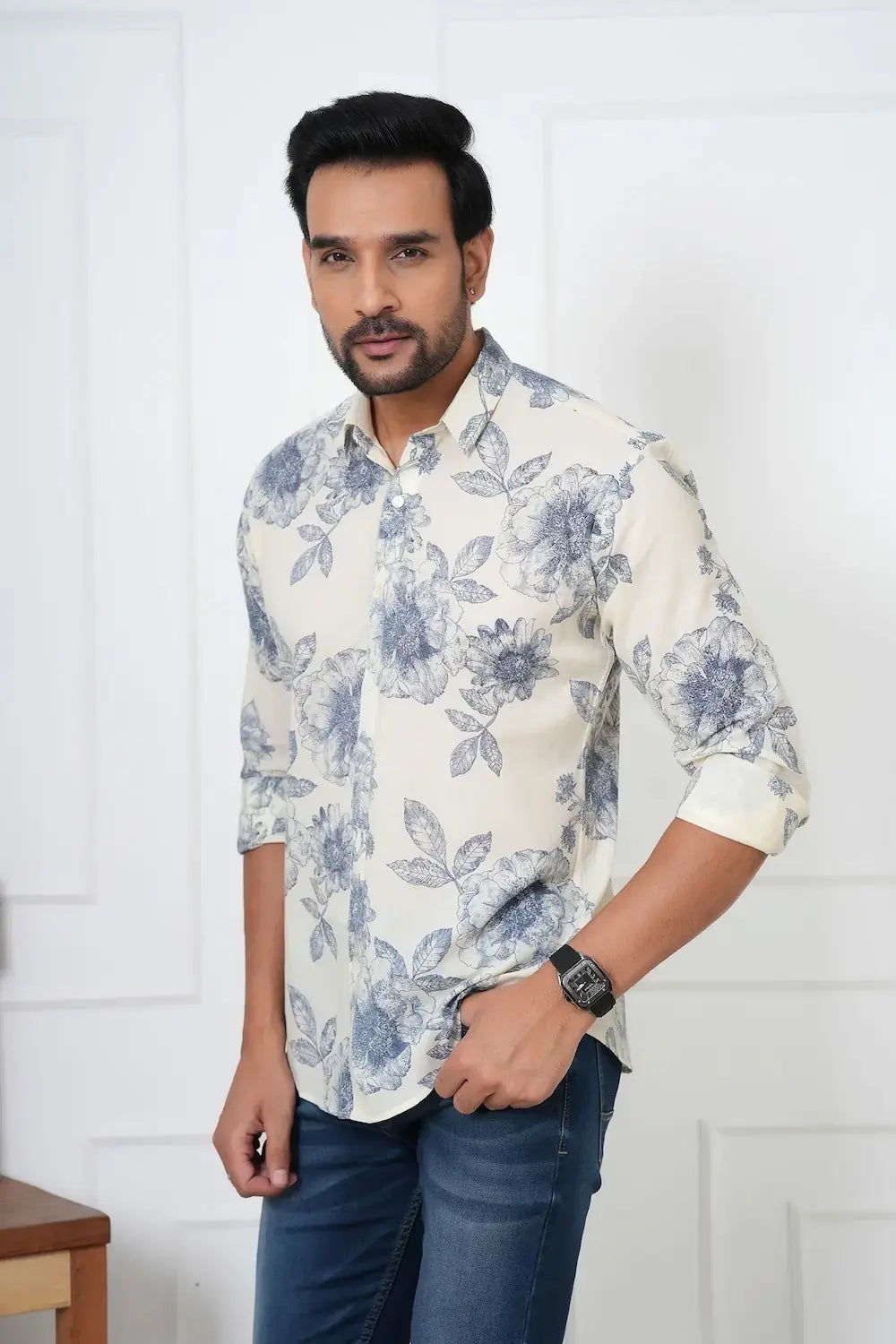 Man wearing a white floral shirt and blue jeans against a white background