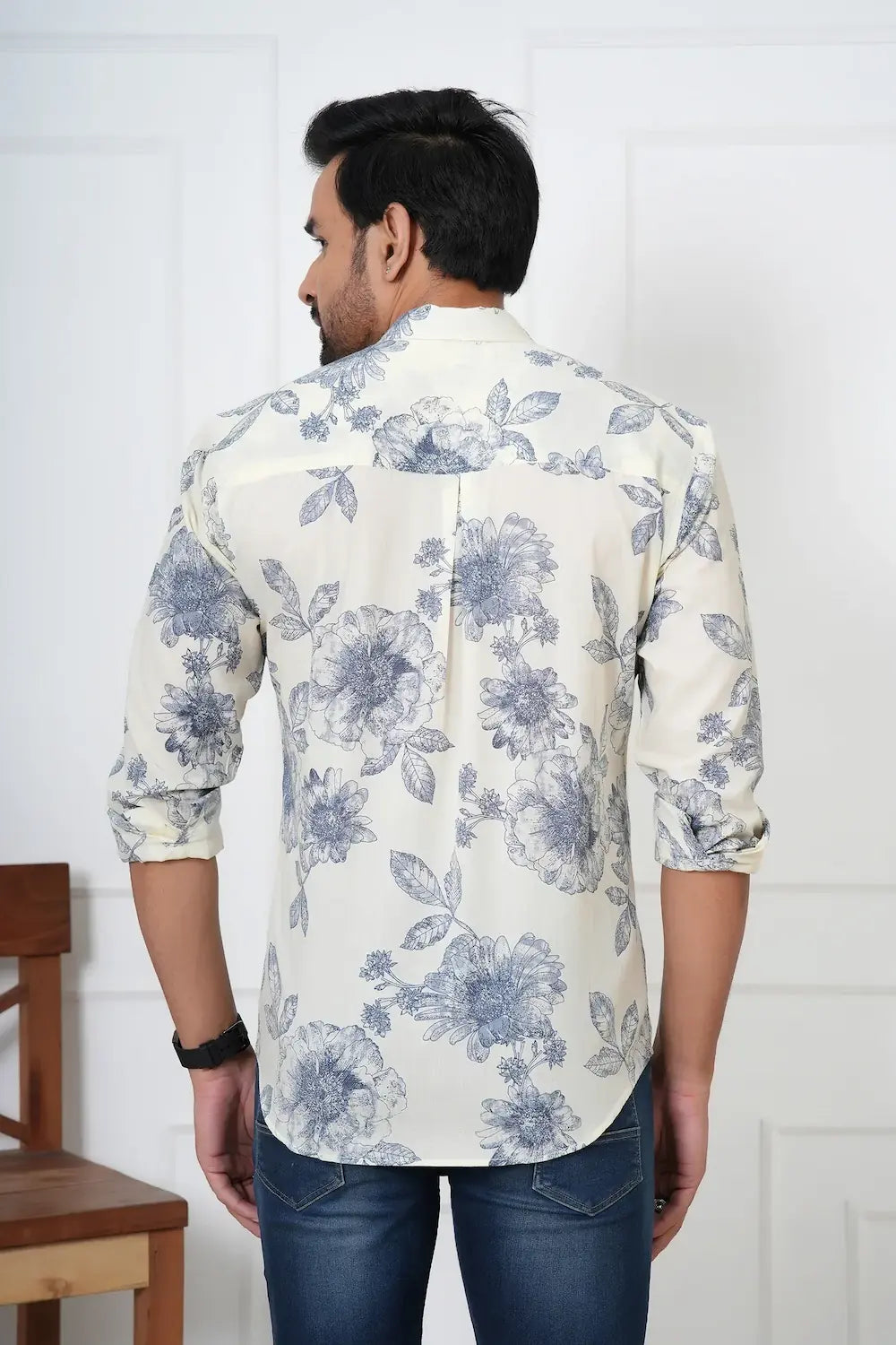 Man wearing a white shirt with blue floral pattern in a room.