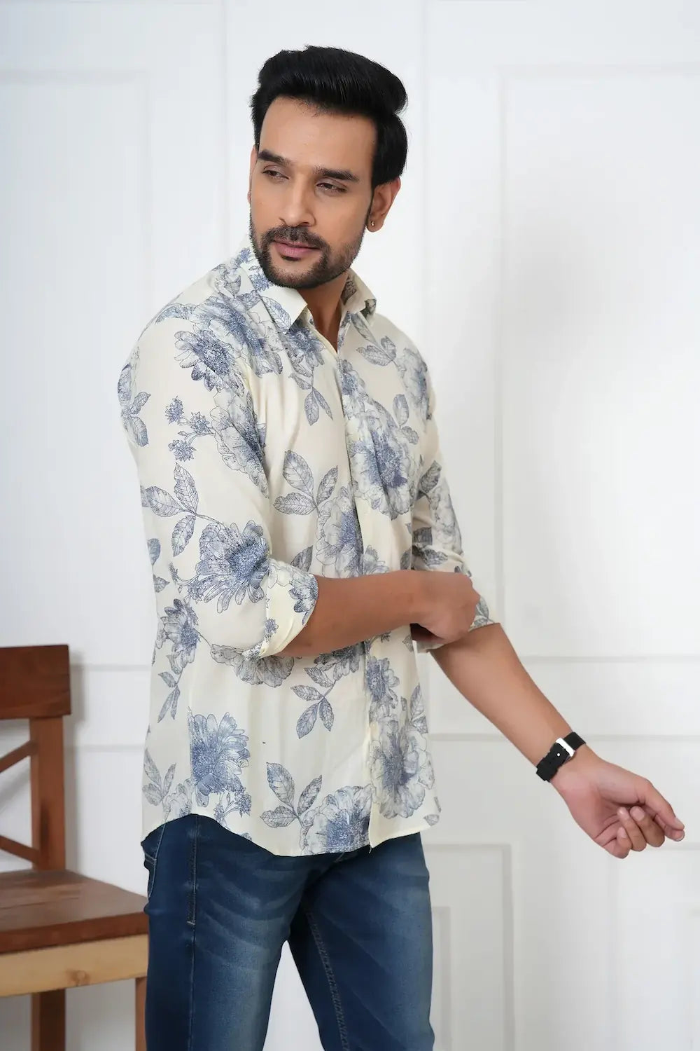 Man wearing a floral shirt and jeans against a white wall