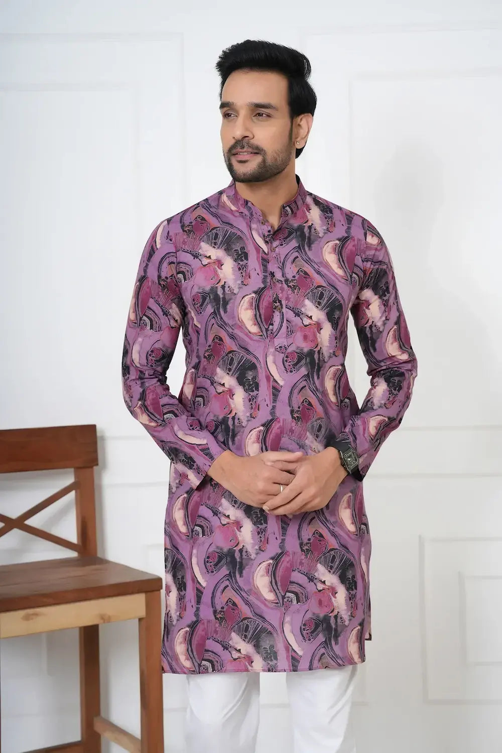 Man wearing a purple patterned kurta with white pants against a white background